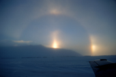 Ice crystals driven by high wind cause a sun pillar, parhelic circle and sun dogs, (parhelia). Wales. Bering Strait. Alaska. 2003