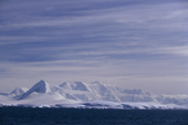 Low ice covered islands in front of the mountains on Wiencke Island. Antarctic Peninsula.