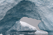 Iceberg with an ice arch on a snowy day. Whittle Peninsula. Antarctica