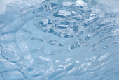Ripples at the heart of a clear piece of glacier ice, trickles of water frozen on its surface like veins. Antarctica