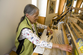 Inuit artist, Igah Etuangat, works on a tapestry at a loom in the Uqqurmiut Centre for Arts & Crafts in Pangnirtung. Nunavut, Canada. 2008