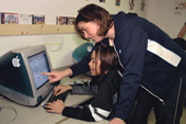 7th Grade Pupil, Beatrice Irngaut, is helped by her teacher during a computer class using an Inuktitut syllabics program at the school in Igloolik. Nunavut, Canada. 2002