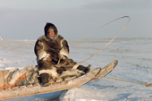 Inuit hunter, Tatigat, dressed in caribou skins, sitting on the front of his sled. Igloolik, Canada. 1993