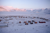 Houses built around the bay in Pangnirtung. Winter sun catches the top of the mountains. Nunavut, Canada. 1993