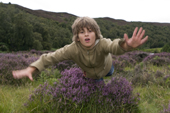Max leaps over a clump of heather in a scottish river valley.