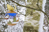 Russian hand painted Christmas decoration hanging on snow covered silver birch tree. England