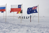 2009 Monaco Antarctic Expedition approaching the Ceremonial South Pole at the end of their overland expedition. Flags of the 12 original Antarctic Treaty nations surround the Pole.