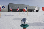 Flags of Nations and the new building by the ceremonial South Pole. Amundsen-Scott South Pole Station. Antarctica