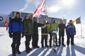 Expedition party standing at the ceremonial South Pole, with a Union Jack Flag. Amundsen-Scott Station. Antarctica