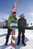 Father and son at the ceremonial South Pole, with a Union Jack Flag. Amundsen-Scott Station. Antarctica