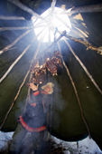 Saami reindeer herder, Nils Peder Gaup, hangs reindeer and moose meat above a fire in his lavo (tent) to smoke it. Kautokeino, Finnmark, North Norway. 2007