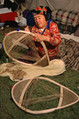 At an Innu hunting camp, Enen, threads caribou skin lacing onto a new pair of snowshoes.Southern Labrador, Canada. 1997