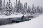 In bad weather, an Innu man travels by canoe to check his traps. Labrador, Canada. 1997