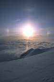 Ice crystals in the upper atmosphere. A pair of parhelia, a sun pillar, the 22 halo, and a hint of the upper tangent arc viewed over the Hayes Range from the Delta Mountains. Eastern Alaska Range.
