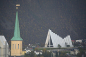 The dramatic Arctic Cathedral in Tromsdalen, built 1965, seen beyond the spire of Troms Cathedral, built in 1861. Norway. 2006