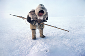 Fur clad Inuk, Qaavigannguaq, waits with his harpoon at a seal's breathing hole. NW Greenland. 1980