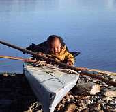 A young Inuit boy plays in a hunter's kayak at a summer hunting camp at Inersussat. Inglefield Bay, Qaanaaq, Thule, Avanersuaq, Northwest Greenland. (1971)