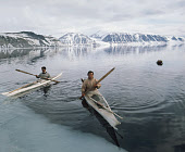 Inuit hunters, Kigutikak (right) and Aserpanguaq, returning to the floe edge in their kayaks towing a Bearded Seal after a successful hunt.Inglefield Bay. Thule, Northwest Greenland. (1971)