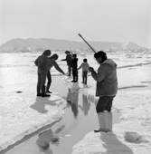 Inuit women and children fishing at a lead in the sea ice during the late Spring. Qaanaaq, Thule, Northwest Greenland. 1971