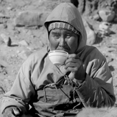 Qalaseq Duneq, an elderly inuk, wearing his waterproof Kayak vest, stops for a cup of tea. Qaanaaq. Thule, Northwest Greenland. 1971