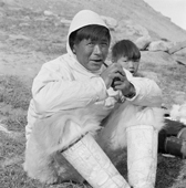 Jess Qujaukitsok in his white camouflage kajak anorak, enjoys a pipe at his summer camp at Inerssussat. Thule, Northwest Greenland. 1971