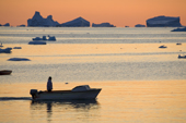 An Inuit hunter, silhouetted in his boat returns home to Qaanaaq at sunset. Inglefield Bay, Northwest Greenland. 2008
