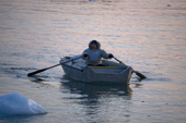 An Inuit hunter rowing his boat ashore at dusk after hunting in Inglefield Bay. Qaanaaq. Northwest Greenland. 2008