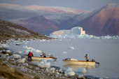 Inuit hunters coming ashore in their boats at dusk after hunting in Inglefield Bay. Qaanaaq. Northwest Greenland. 2008