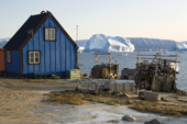 A very large iceberg floats in Inglefield Bay behind an Inuit hunter's home in Qaanaaq. Northwest Greenland. 2008