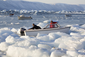 Inuit hunters moving their boat through glacial ice along the coast of Inglefield Bay in autumn. Qaanaaq, Northwest Greenland. 2008