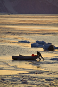 At sunset, an Inuit hunter manoevres his boat through newly formed sea ice. Autumn in Inglefield Bay. Qaanaaq, Northwest Greenland. 2008