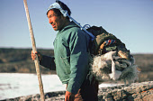 Jakob Petersen, an Inuit hunter, hikes overland to a summer Narwhal hunting camp on the coast of Qeqertat Island. Inglefield Bredening, Thule, Avanersuaq. Northwest Greenland. (1977)