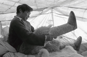 Kaugunak Qissuk pulls on his kamik in his tent while out hunting. Northwest Greenland. 1977