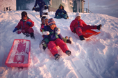 Warmly dressed Inuit children play on toboggans Savissivik. NW Greenland. 1991