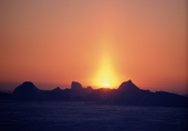 Caused by ice crystals in the air, a sun pillar glows above icebergs in Melville Bay. Northwest Greenland. 1998