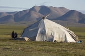 Chukchi children playing outside a Yaranga (traditional tent) at a reindeer herders' summer camp on the tundra with mountains of the Chukotsky Range in the backgrounds. Iultinsky District, Chukotka, Siberia, Russia