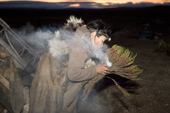 At the beginning of the Chukchi 'Festival of the Young Reindeer,' at 3am, Tamara, blows on a bunch of dried Arctic Bell Heather, to start a ritual fire. Iultinsky District, Chukotka, Siberia, Russia.