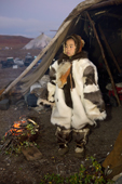 Nadia Takui, a Chukchi girl, dressed in a new Kerker (reindeer skin coverall) stands by a ritual fire at the entrance of a Yaranga (tent) at the start of the Chukchi 'Festival of the Young Reindeer' at a herders' summer camp. Iultinsky District, Chukotka, Siberia, Russia.
