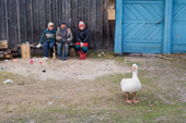 Children seated outside a house in Pogost village watch a goose wander by. Ryazan Province, Russia. 2006