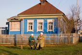 Two elderly women chat while sitting on a bench outside a wooden house in the village of Giblitsy. Ryazan Province, Russia. 2006