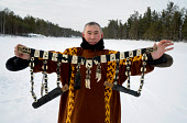 Vassilly Pyak, a Forest Nenets reindeer herder, holds up his traditional man's belt (Nivija) he made. On it are knives, tools and amulets. It is decorated with carved plates made from moose antler. Numto, Khanty Mansiysk, Northwest Siberia, Russia