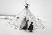 Nenets woman and boy stand by a snow covered reindeer skin tent. Yamal. Siberia. 1993
