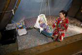 Olga Piak, a Forest Nenets woman, rocks her baby son in a traditional cradle inside their tent. Purovsky region, Yamal, Western Siberia, Russia