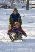 Two Forest Nenets girls playing with a toboggan at a winter camp in the Purovsky region of the Yamal. Western Siberia, Russia.