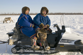 Nenets men sitting on a snowmobile at a reindeer herders festival in the Yamal. Western Siberia, Russia
