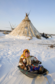 Yaline Laptander, a young Nenets girl, playing with a toboggan at her family's winter camp in the Yamal. Western Siberia, Russia