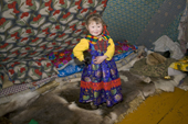 Yaline Laptander, a Nenets girl, playing with a puppy inside a reindeer skin tent at her family's winter camp in the Yamal. Western Siberia, Russia