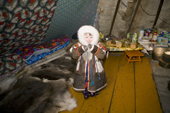 Yaline Laptander, a Nenets girl, putting on her reindeer skin coat inside a tent at her family's winter camp in the Yamal. Western Siberia, Russia