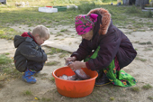 Lidiya, a Khanty woman, cleans fish at a camp on the River Ob, watched by her grandson, Artiom. Yamal, Western Siberia, Russia.