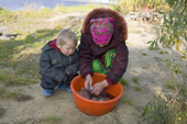 Lidiya, a Khanty woman, cleans fish at a camp on the River Ob, watched by her grandson, Artiom. Yamal, Western Siberia, Russia.